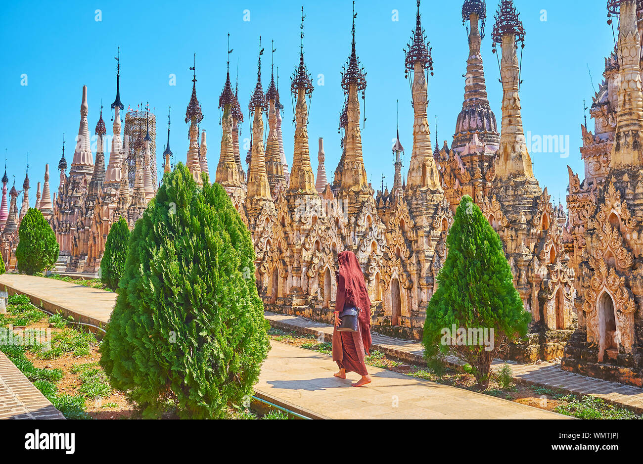 Le moine bhikkhu en habit rouge promenades le long de la rangée de stupas funéraires ancinet, préservés dans les pagodes Myanmar Kakku site, Banque D'Images