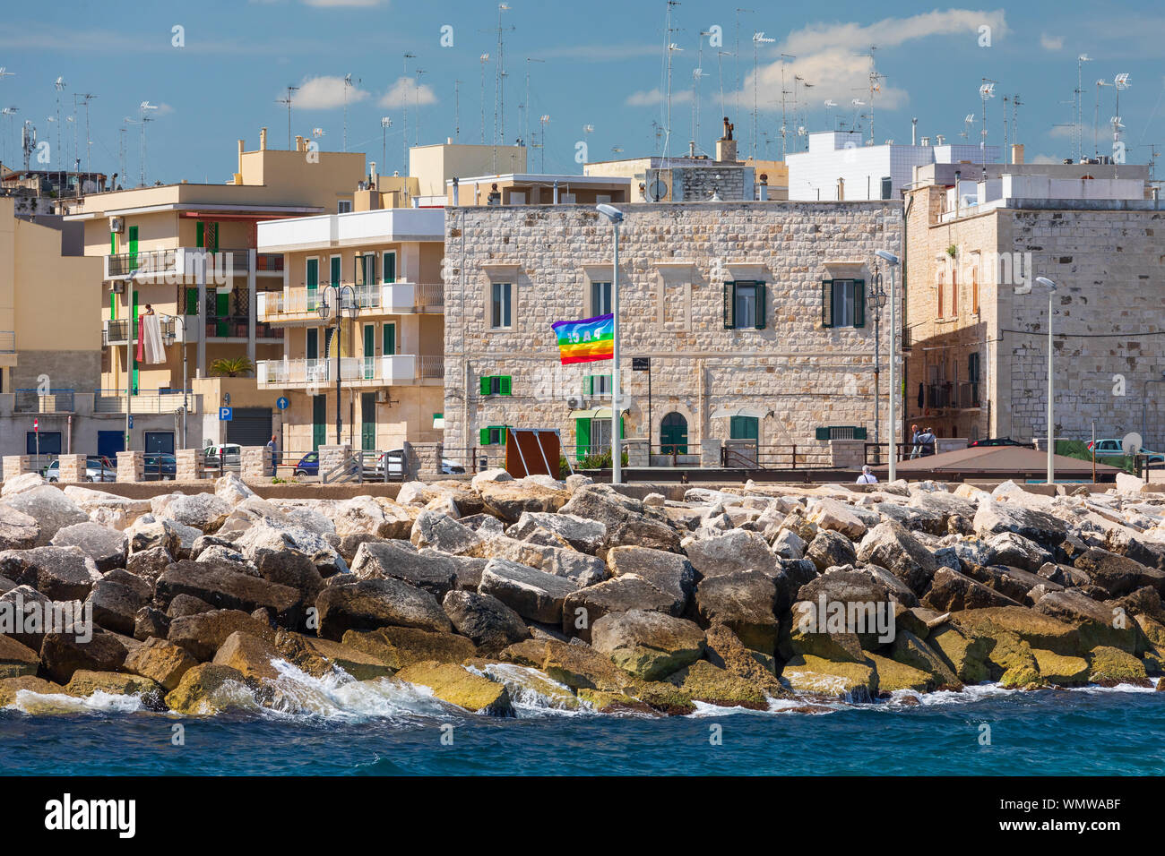Italie, Pouilles, l'agglomération de la ville de Bari, Cagliari. Bâtiments le long du front de mer. Drapeau arc-en-ciel avec le mot 'espace' qui signifie 'la paix.' Banque D'Images