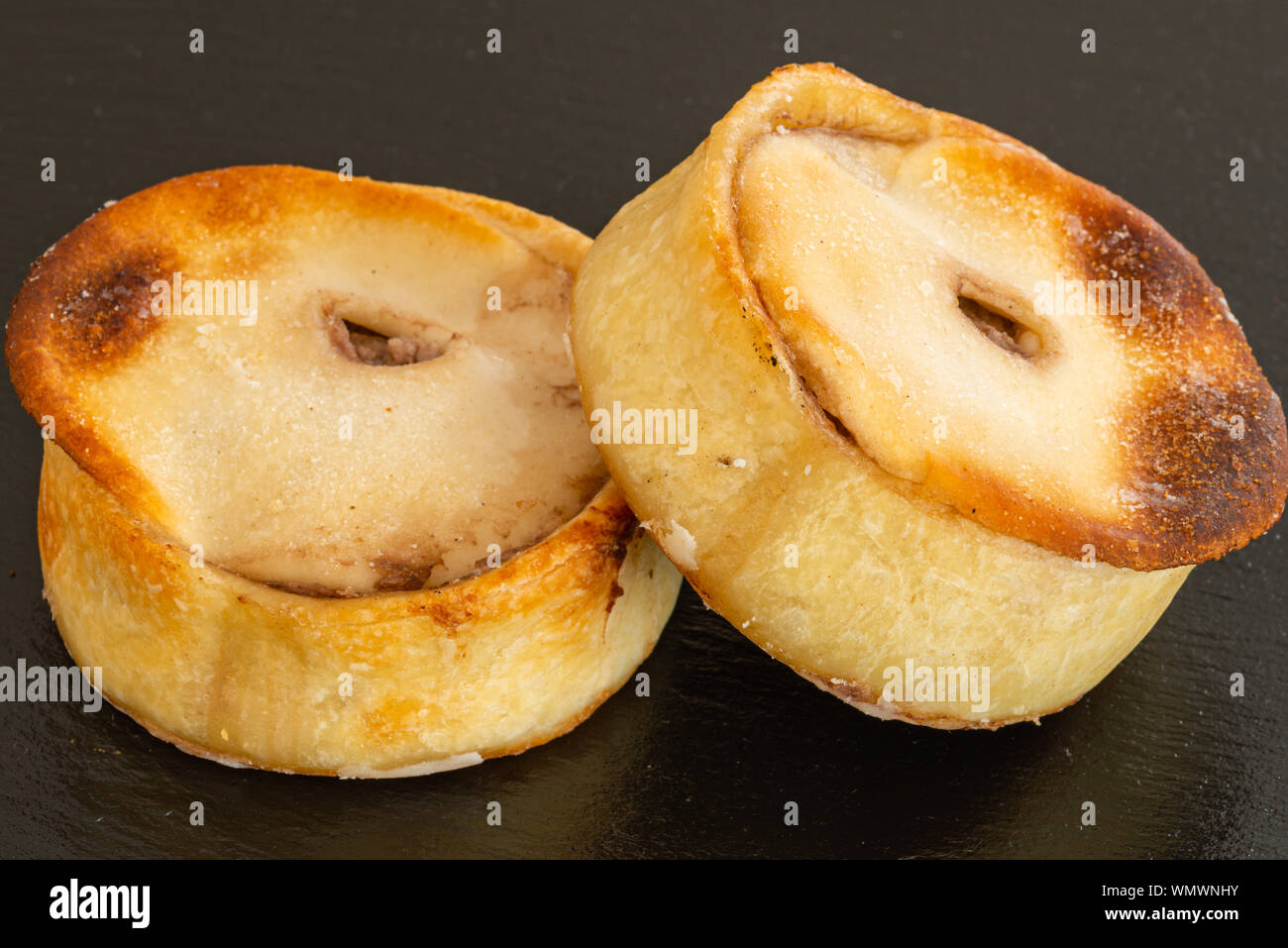 Deux Scotch pies juste du four et servie sur une assiette de service en ardoise noire. Banque D'Images