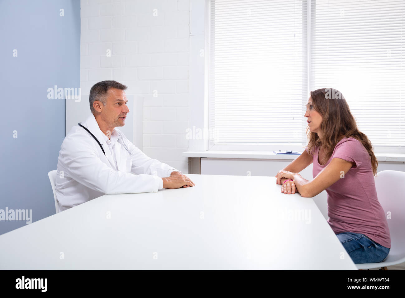 Vue de côté Mature Doctor Sitting with Female Patient In Clinic Banque D'Images