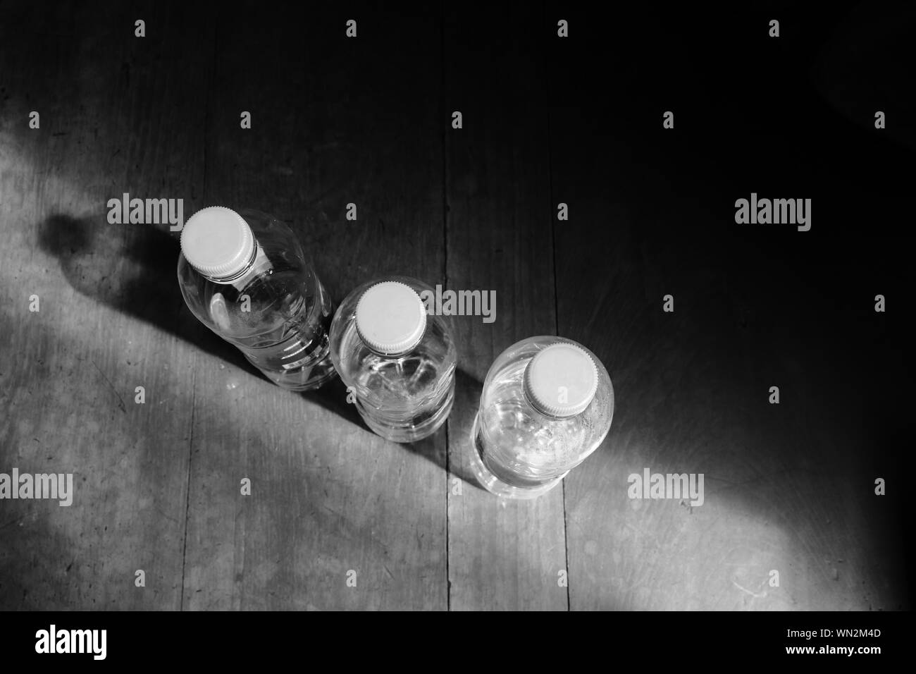 Libre de bouteilles vides en plastique sur la surface en bois sous la lumière du soleil, les déchets en plastique, les déchets hors du concept. Noir et blanc photo, high angle view, sel Banque D'Images