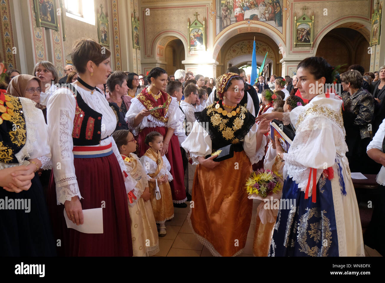 Des gens habillés en costumes folkloriques régionaux traditionnels dans l'église à la messe le jour de Thanksgiving à Stitar, Croatie Banque D'Images