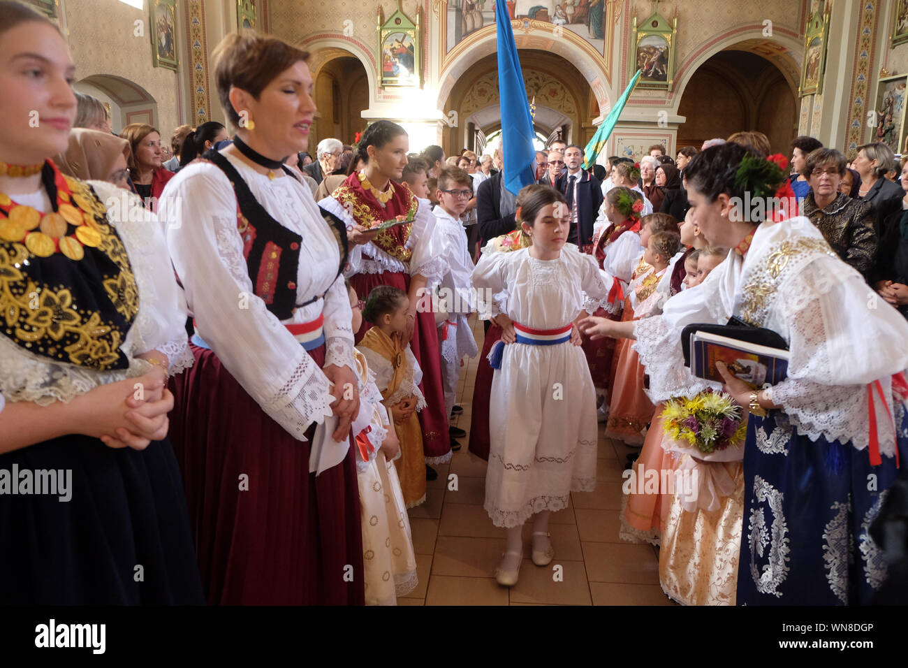 Des gens habillés en costumes folkloriques régionaux traditionnels dans l'église à la messe le jour de Thanksgiving à Stitar, Croatie Banque D'Images