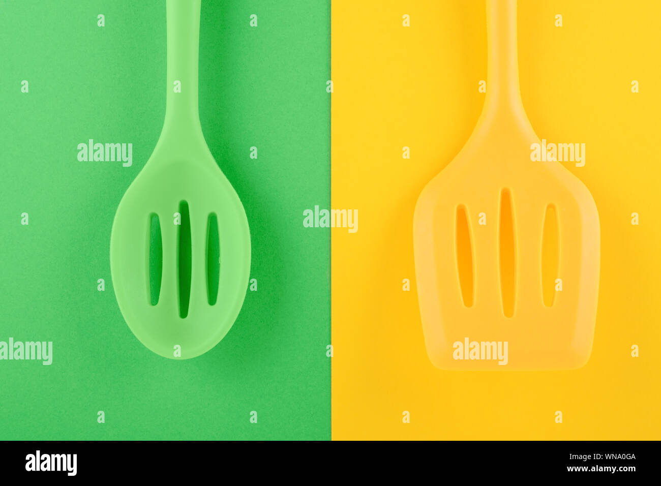 Les ustensiles de cuisine lumineuse sur fond vert et jaune, idée créative Banque D'Images