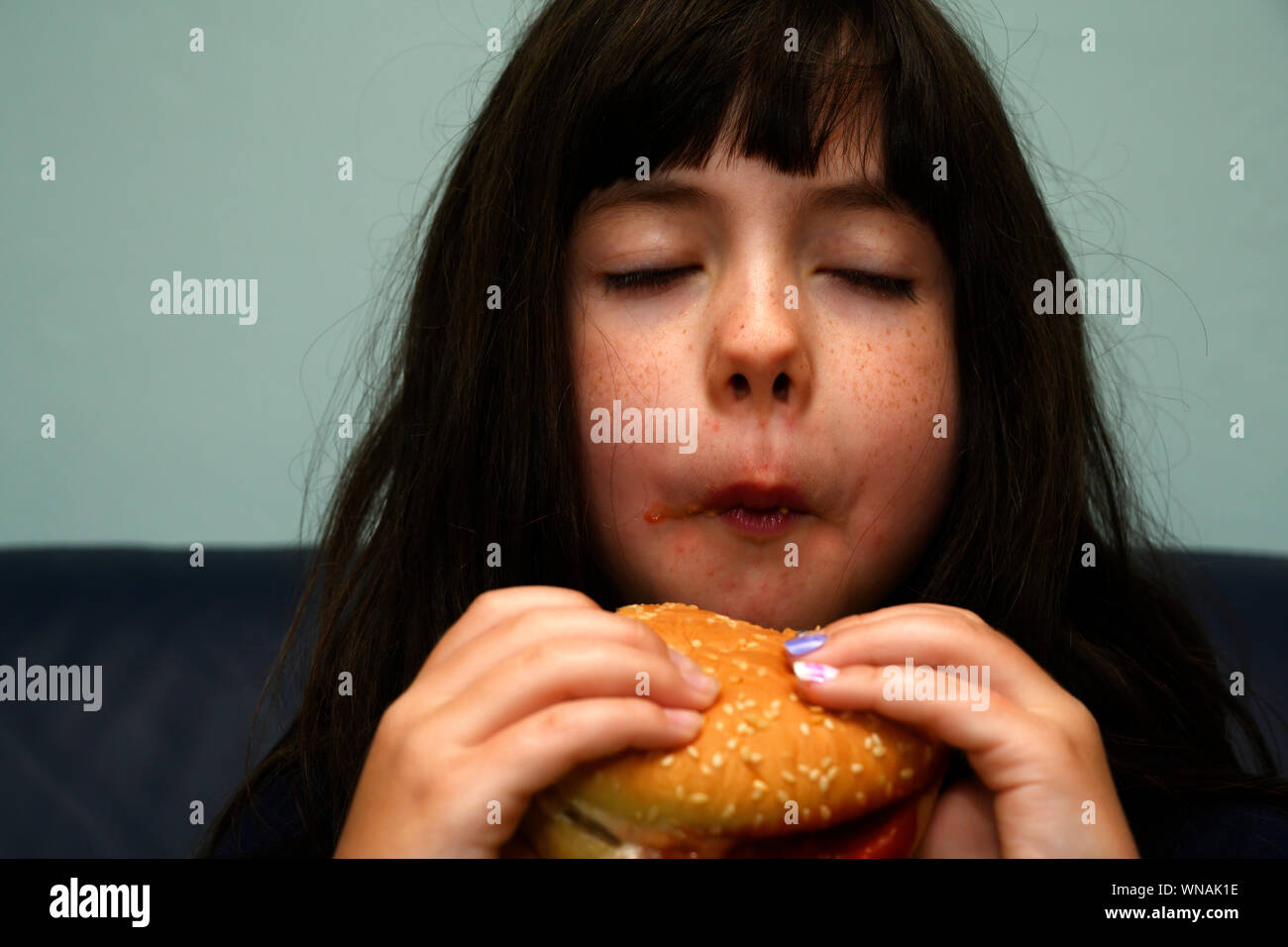 7-year old girl eating hamburger Banque D'Images