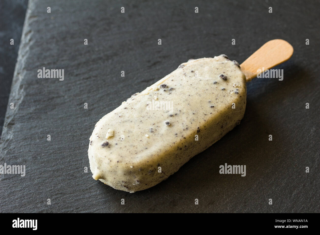 Sucette de crème glacée au chocolat blanc et chocolat noir revêtement de cookie isolé sur fond noir Banque D'Images