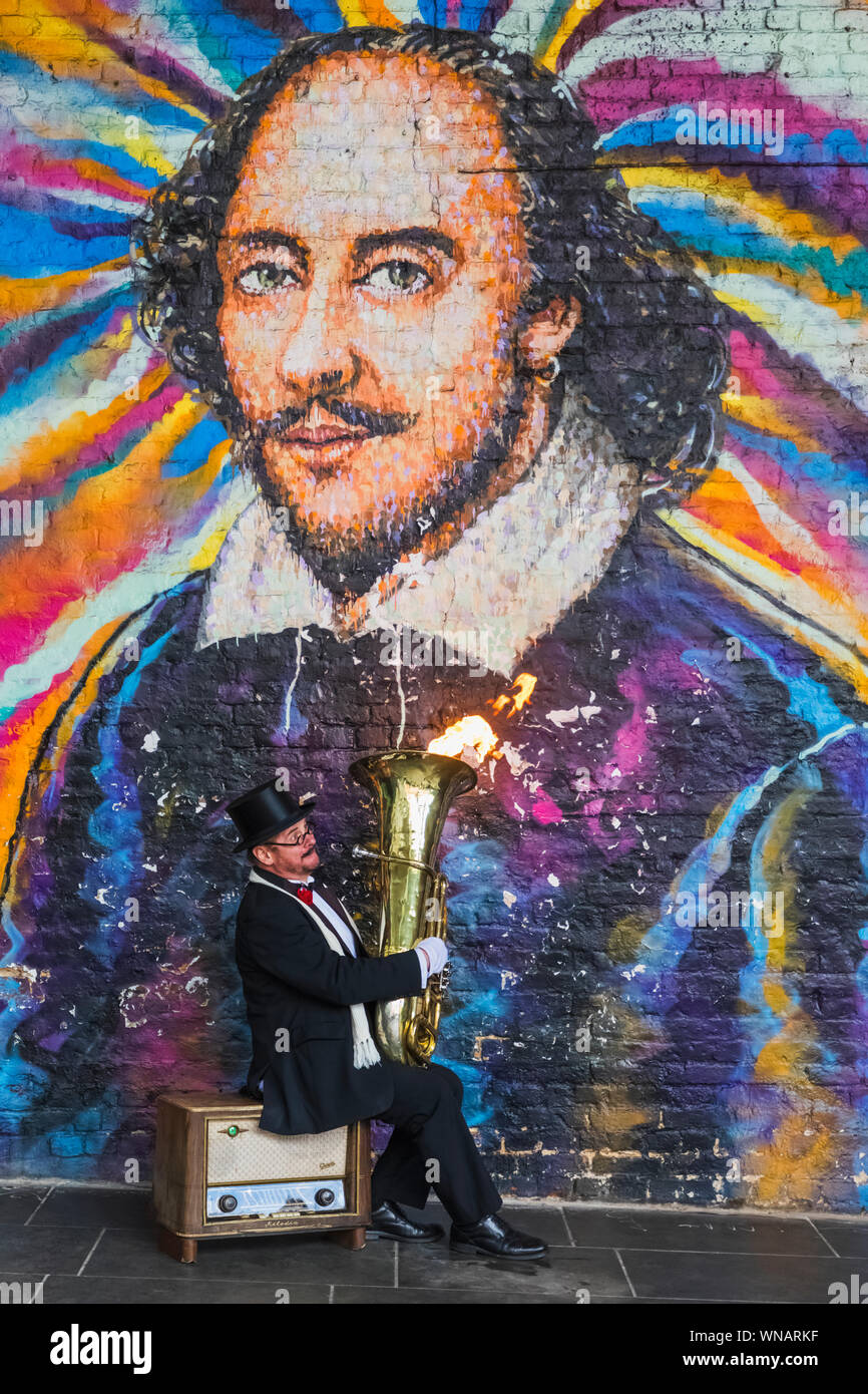 L'Angleterre, Londres, Southwark, Bankside, Musicien de rue jouer Fire soufflant tuba en face de William Shakespeare-Mural Banque D'Images