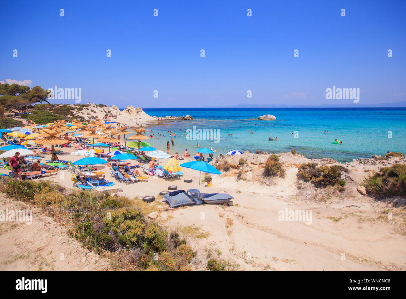 Belle plage de sable avec rochers et la formation d'eau de mer propre turquoise . Les gens profiter des vacances touristiques sur chaude journée. La Grèce. Banque D'Images