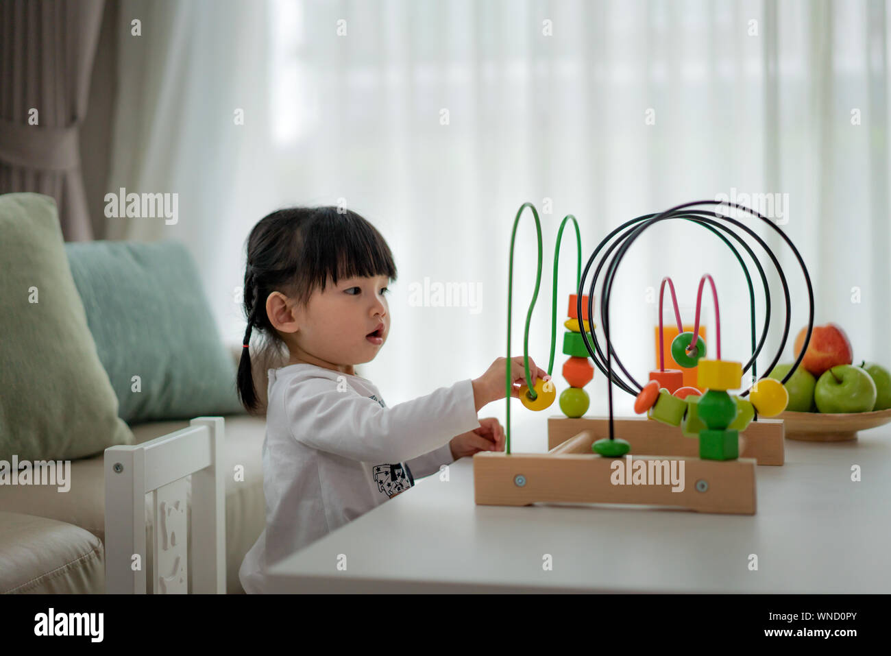 Tout-petits Asie adorable baby girl sitting on chair et en jouant avec des jouets de couleur à la maison. Banque D'Images