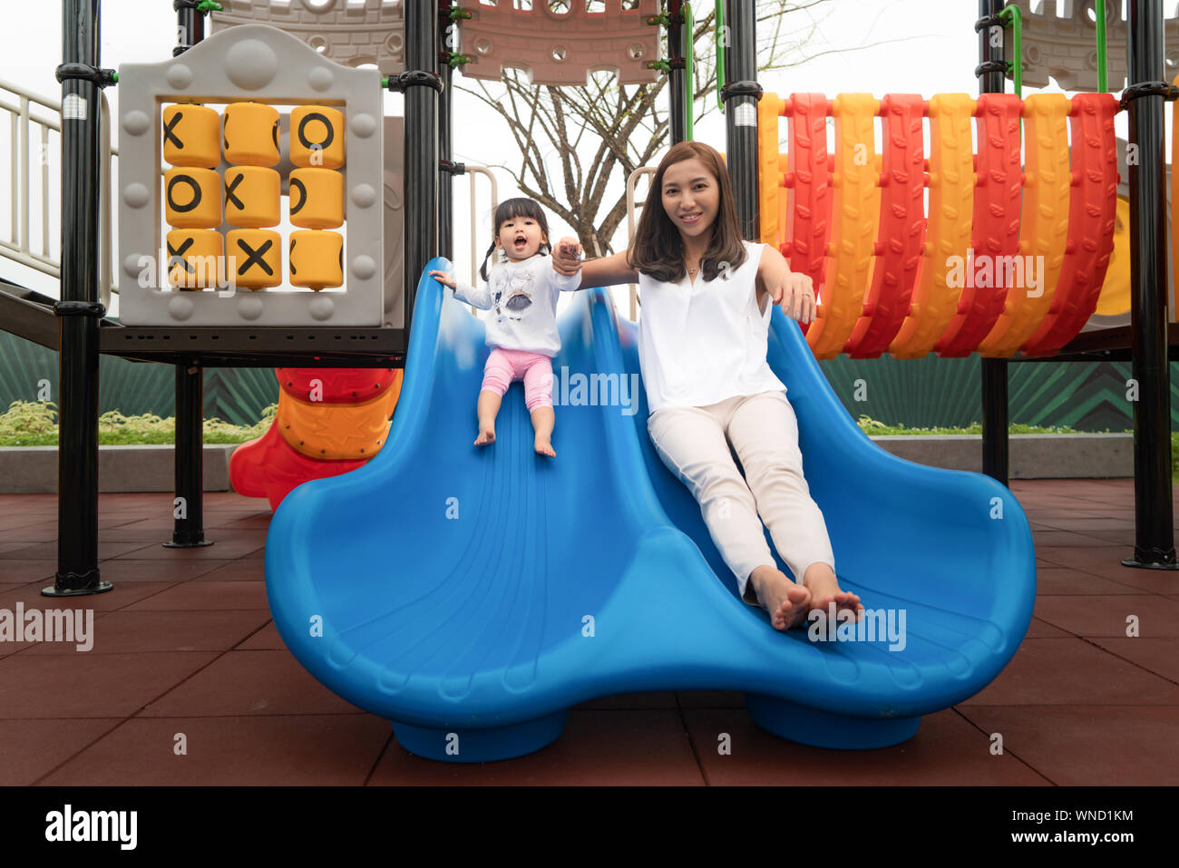 La mère et la fille sont asiatiques de bonheur et de plaisir à jouer ensemble dans l'équipement glisser jeux pour enfants, avec bonheur pleinement actuellement. Concept de famille heureuse. Banque D'Images