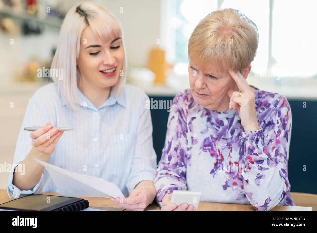 Woman Helping Confused Senior voisin avec la paperasserie et les finances publiques Banque D'Images