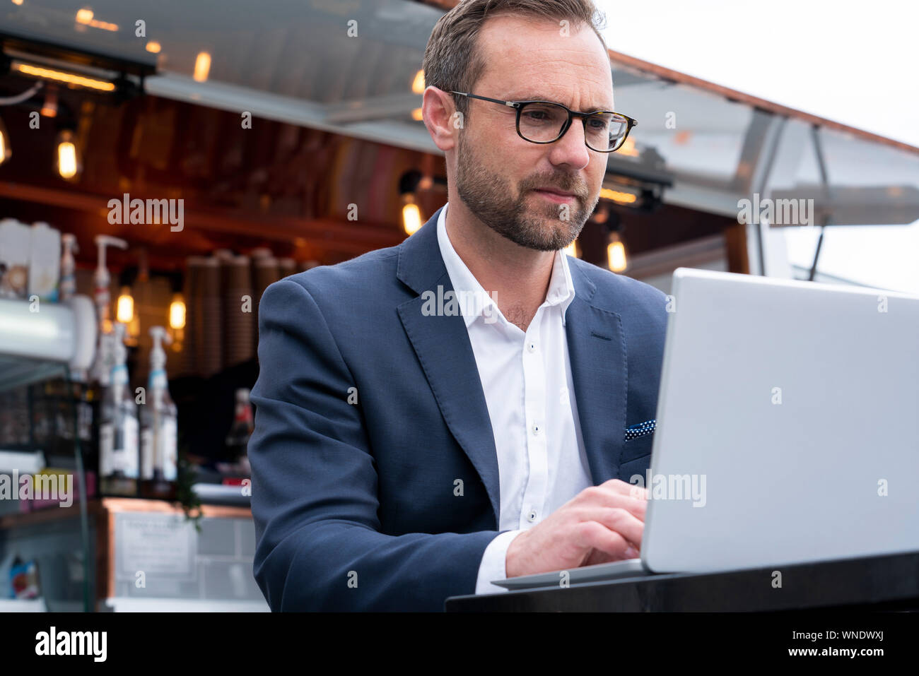 Mature Businessman Working On Laptop par Café-restaurant en plein air Banque D'Images