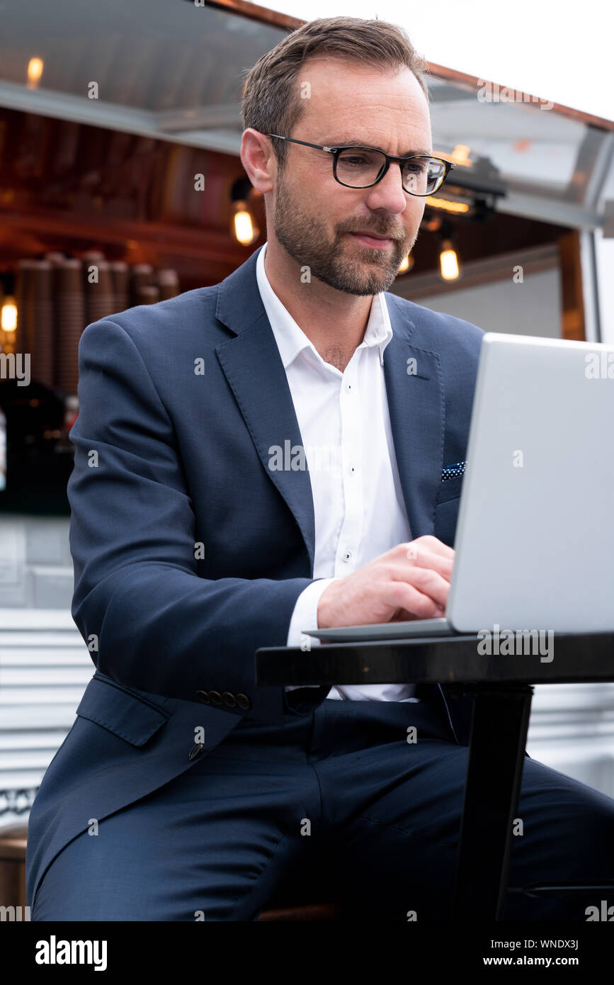 Mature Businessman Working On Laptop par Café-restaurant en plein air Banque D'Images
