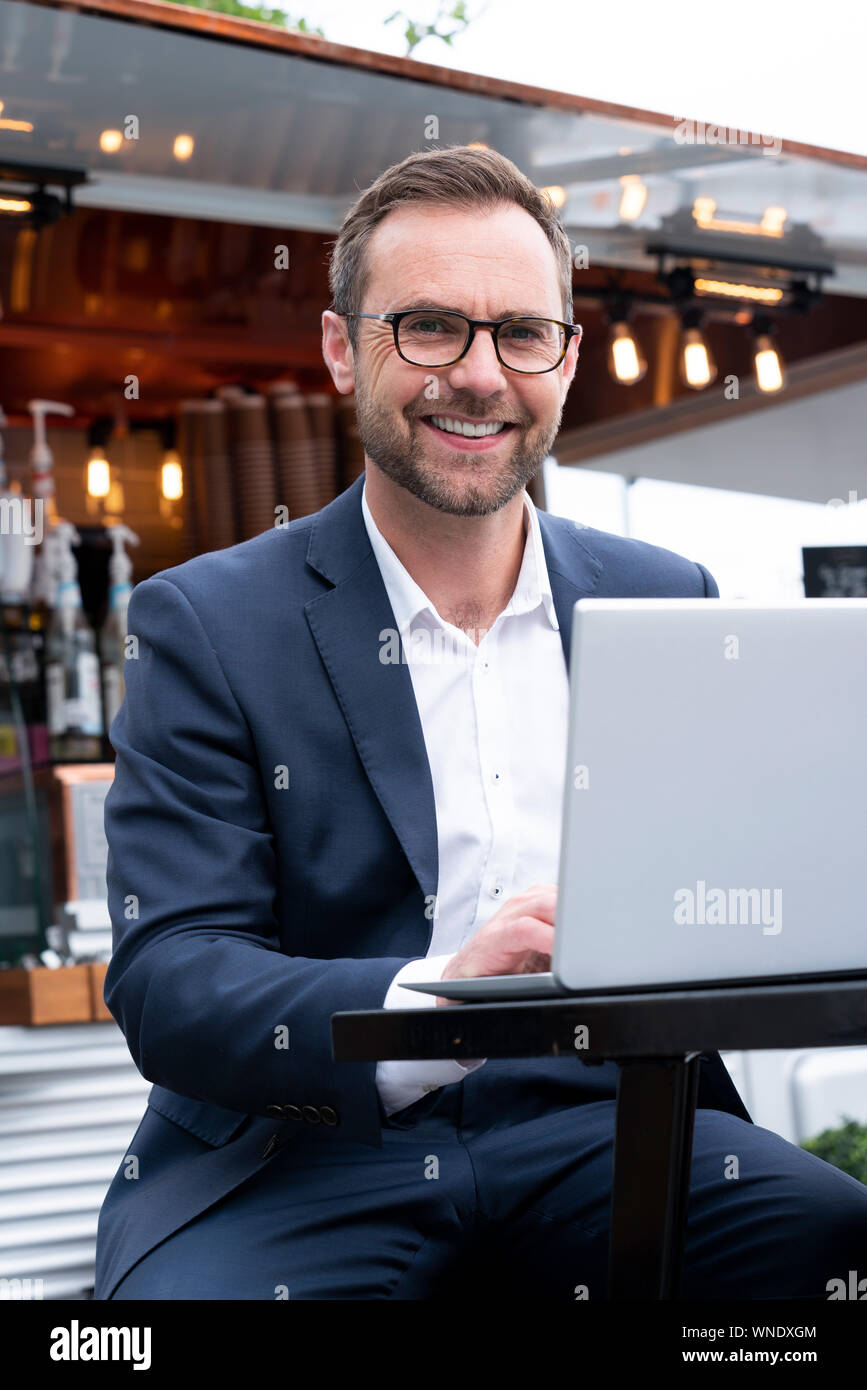 Portrait Of Mature Businessman Working On Laptop par Café-restaurant en plein air Banque D'Images