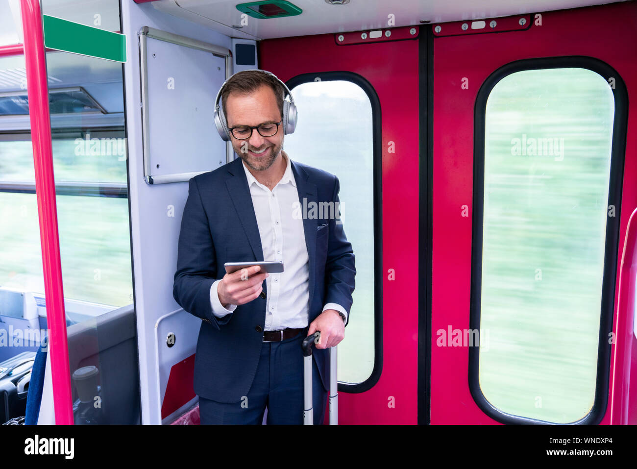 Businessman Standing On Train Film Streaming à partir d'un téléphone  portable sur un casque sans fil Photo Stock - Alamy