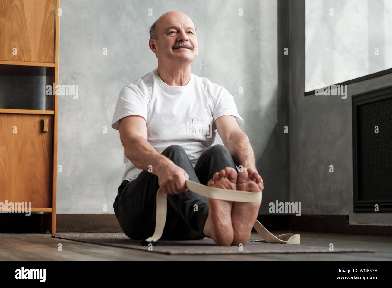 Young man sitting in paschimottanasana ou intense Étirement dorsal posent, assis flexion avant la posture, l'exercice pour les hanches et la colonne vertébrale à la maison usin Banque D'Images
