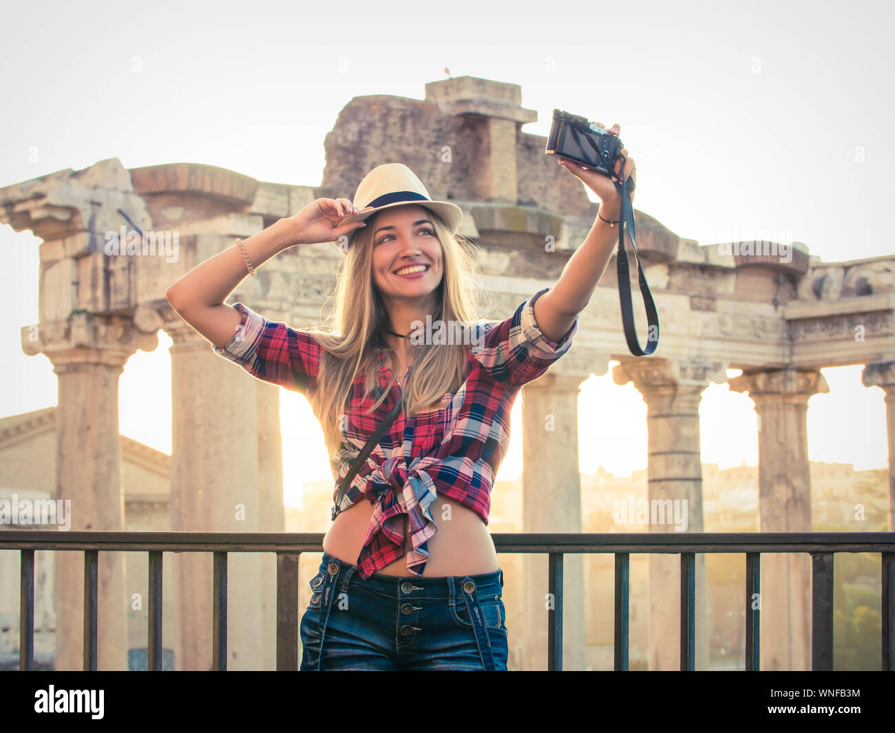 Jeune femme blonde aux cheveux longs et les yeux bleus en tenant vos autoportraits avec vintage camera au Forum romain au lever du soleil. Rome, Italie Banque D'Images