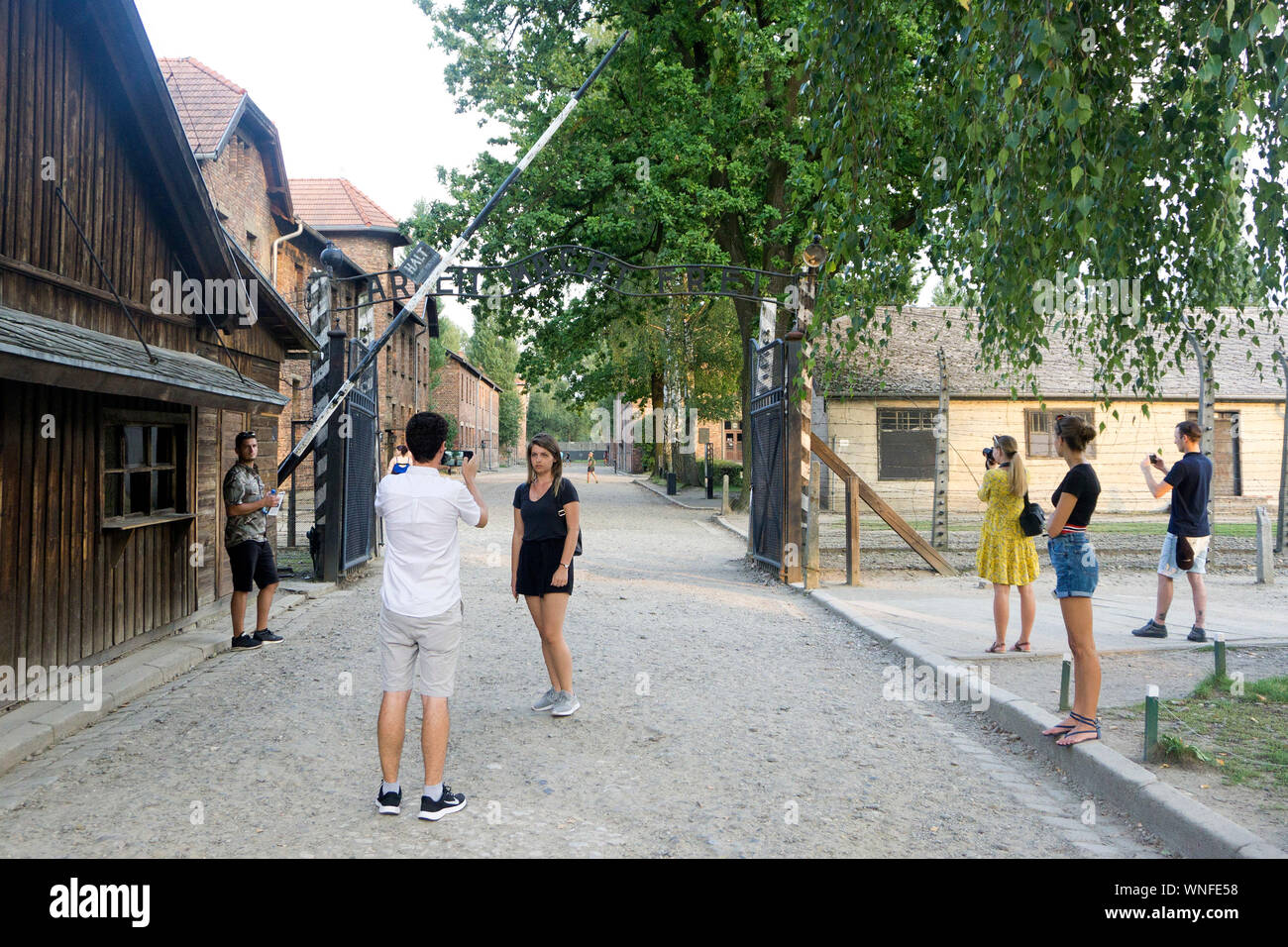 Un visiteur pose pour une photo à la porte de 'Arbeit macht frei' au camp de concentration d'Auschwitz et en Pologne, le 29 août 2019. Banque D'Images