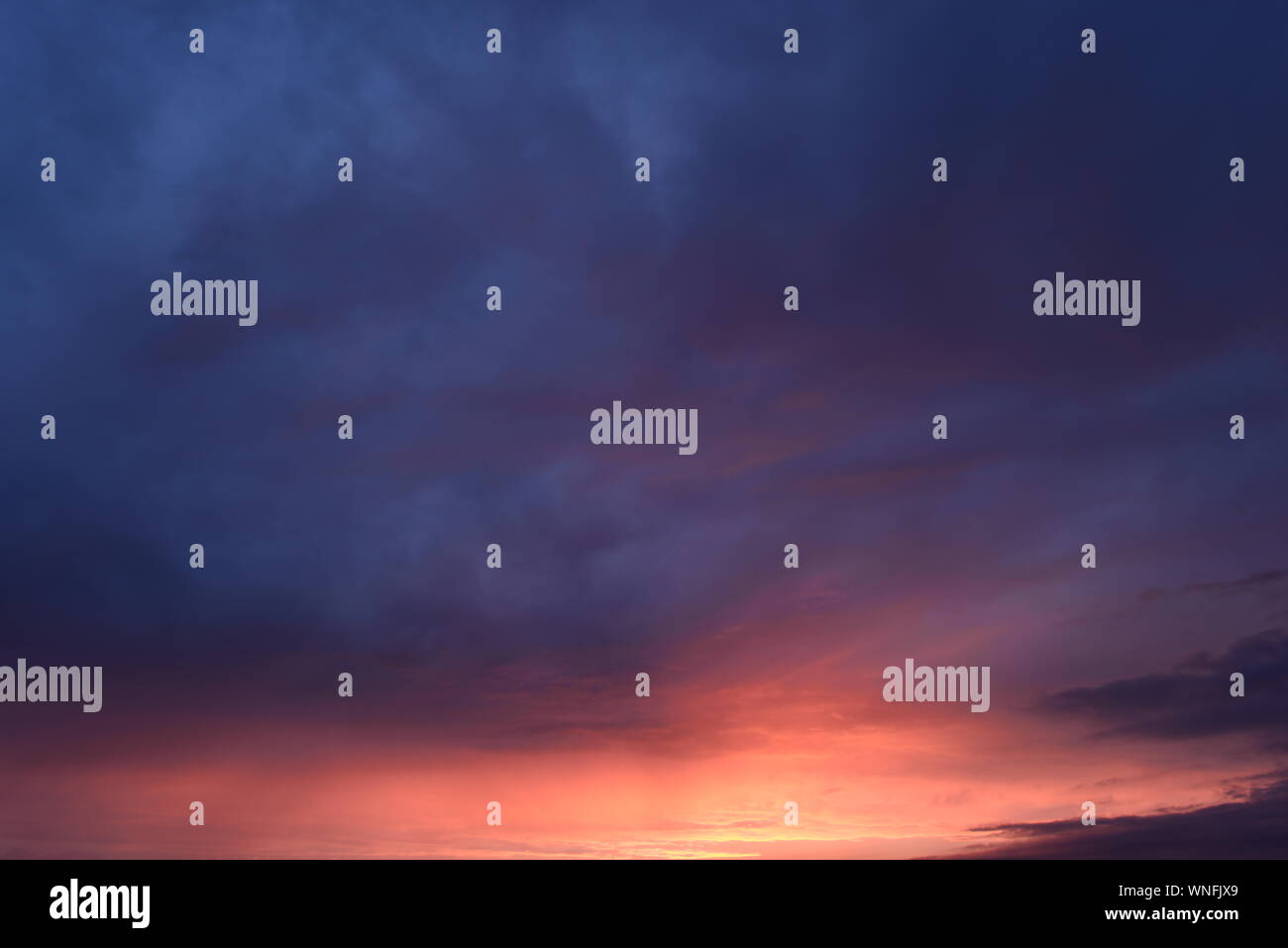 Ciel nuageux Ciel bleu dans le jaune et rouge lumineux du soleil de coucher du soleil Banque D'Images