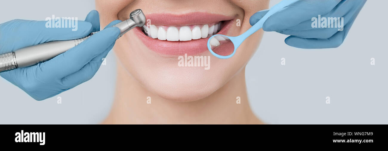 Portrait sourire parfait et dentiste mains tenant une fraise dentaire et un angle miroir. Traitement des dents et la dentisterie Banque D'Images