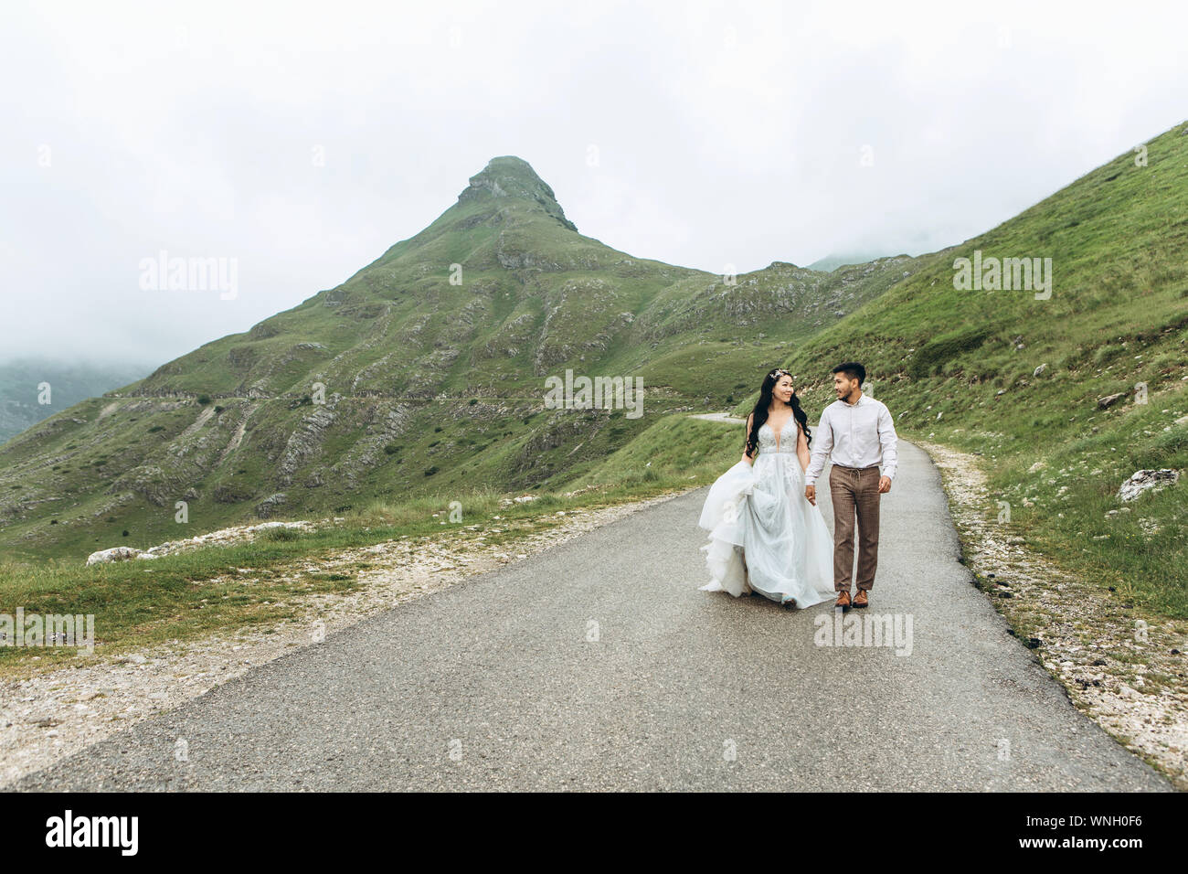 Les mariés sont sur la route dans les highlands. Mariage dans les montagnes. Banque D'Images