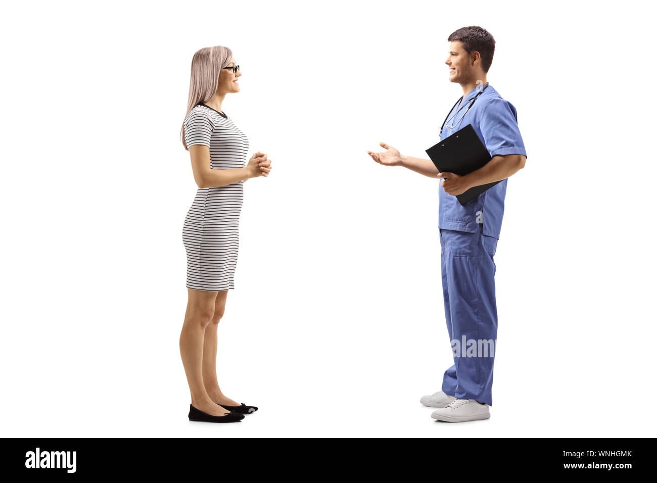 Profil de pleine longueur de balle un jeune médecin homme dans un uniforme bleu de parler à une jeune femme isolée sur fond blanc Banque D'Images
