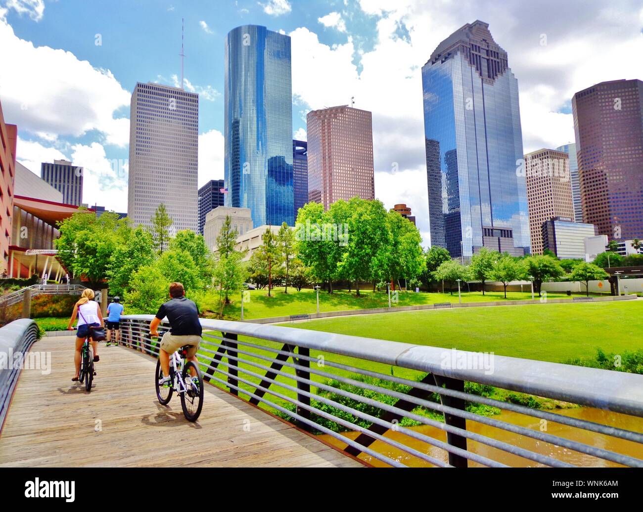 Les cyclistes contre pont de bois dans la région de Buffalo Bayou Parc, avec une belle vue sur le centre-ville de Houston (skyline / gratte-ciel) en arrière-plan un jour d'été Banque D'Images