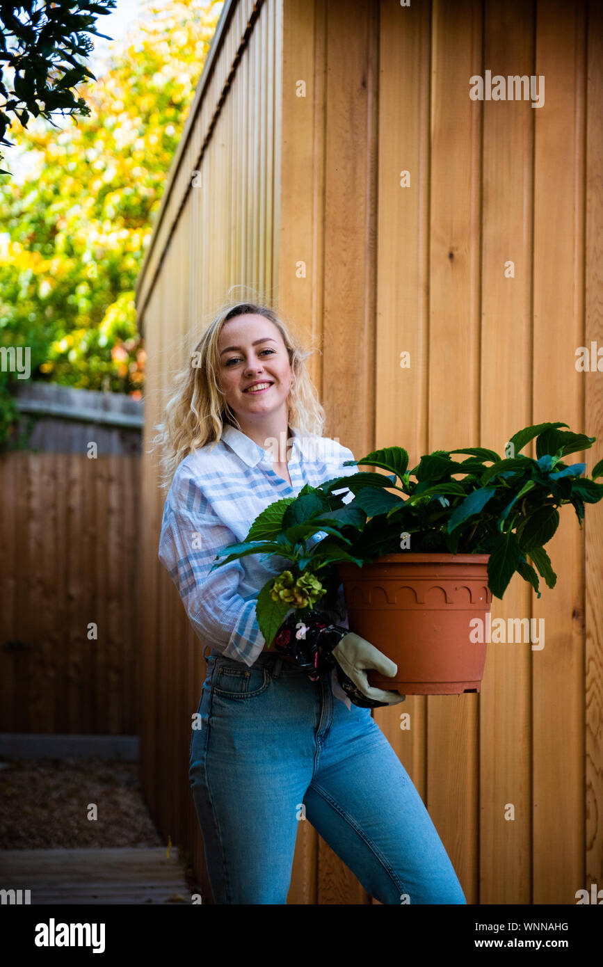 Jardinage plantes en pot modèle avec cat company contre un bois de cèdre bardage maison jardin Banque D'Images
