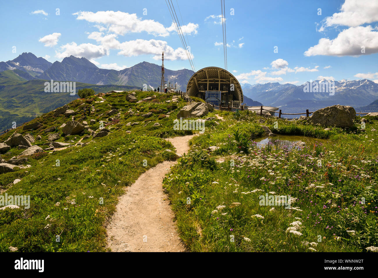 Vue sur le Jardin Botanique Alpin Saussurea Skyway de téléphérique Monte Bianco avec un sentier et un petit étang en été, Courmayeur, Aoste, Italie Banque D'Images