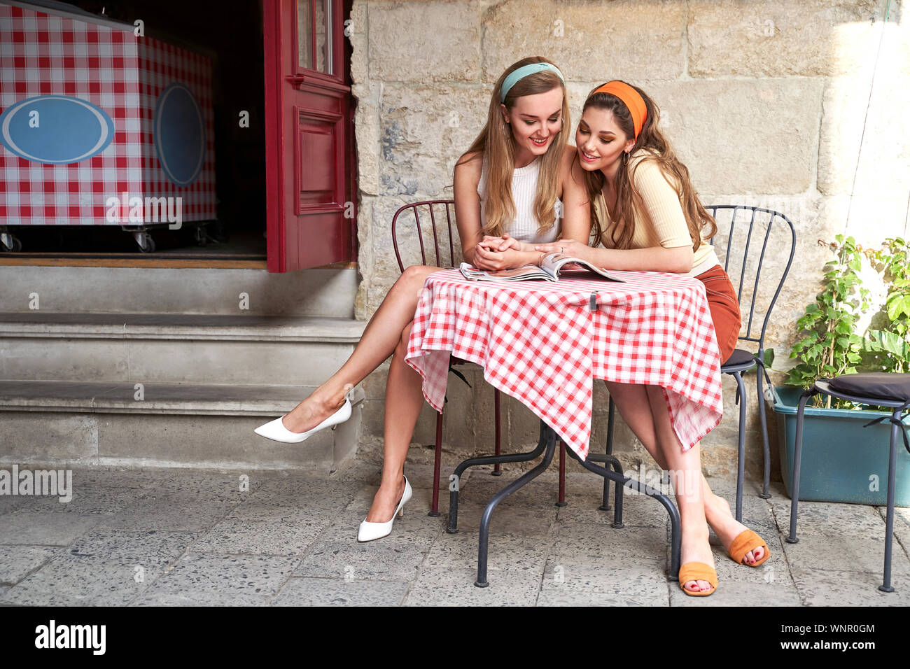 Les jeunes belles filles vêtues de style vintage retro profiter de la vieille ville européenne vie lire un magazine en street cafe Banque D'Images