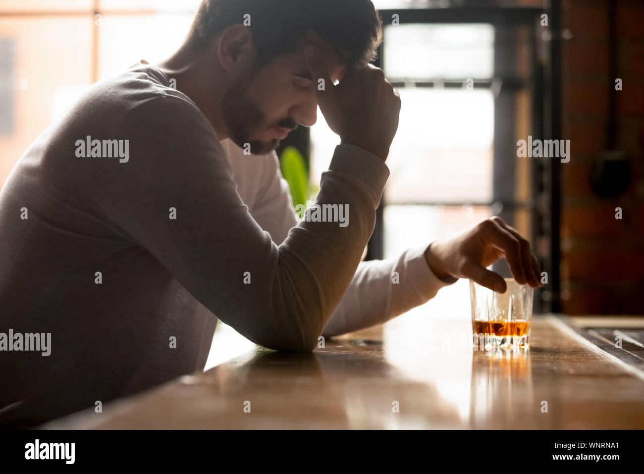 A souligné l'homme ivre assis seul avec verre de whisky en bar Banque D'Images