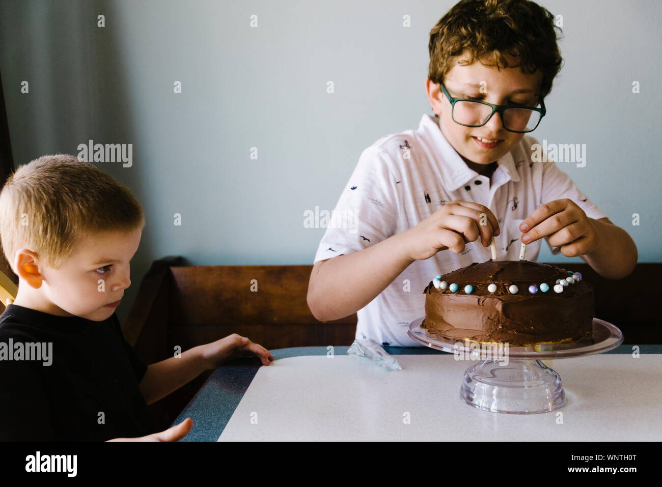 Le Tween boy decorating son gâteau d'anniversaire à la maison avec son neveu. Banque D'Images