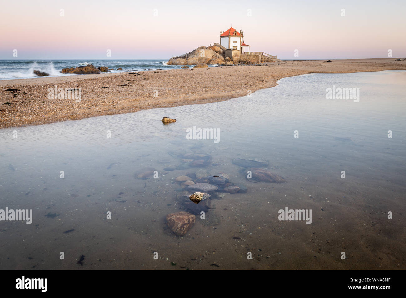 Lever du soleil sur la plage avec une église dans la mer (Chapelle) Senhor da Pedra Banque D'Images