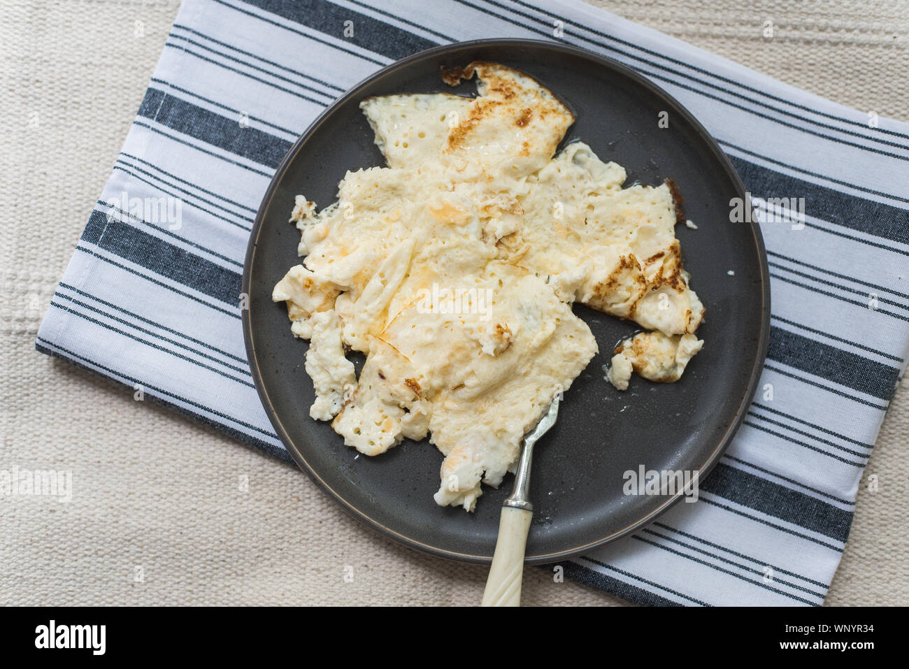 Omelette d'oeuf et de lait fait maison sur une plaque en céramique sur une  serviette. Un petit-déjeuner maison droite Photo Stock - Alamy