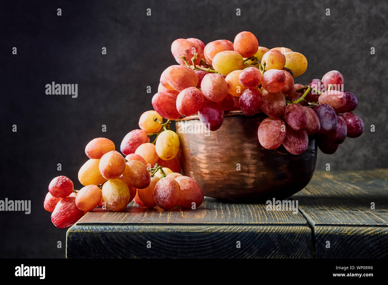 Les raisins frais. Bouquets de différentes variétés dans une assiette sur une vieille table en bois et un arrière-plan sombre. soft focus Banque D'Images