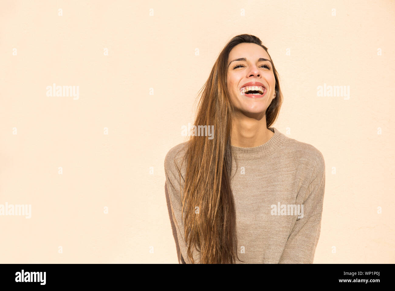 Laughing woman appuyé contre un mur à Boadilla del Monte Banque D'Images