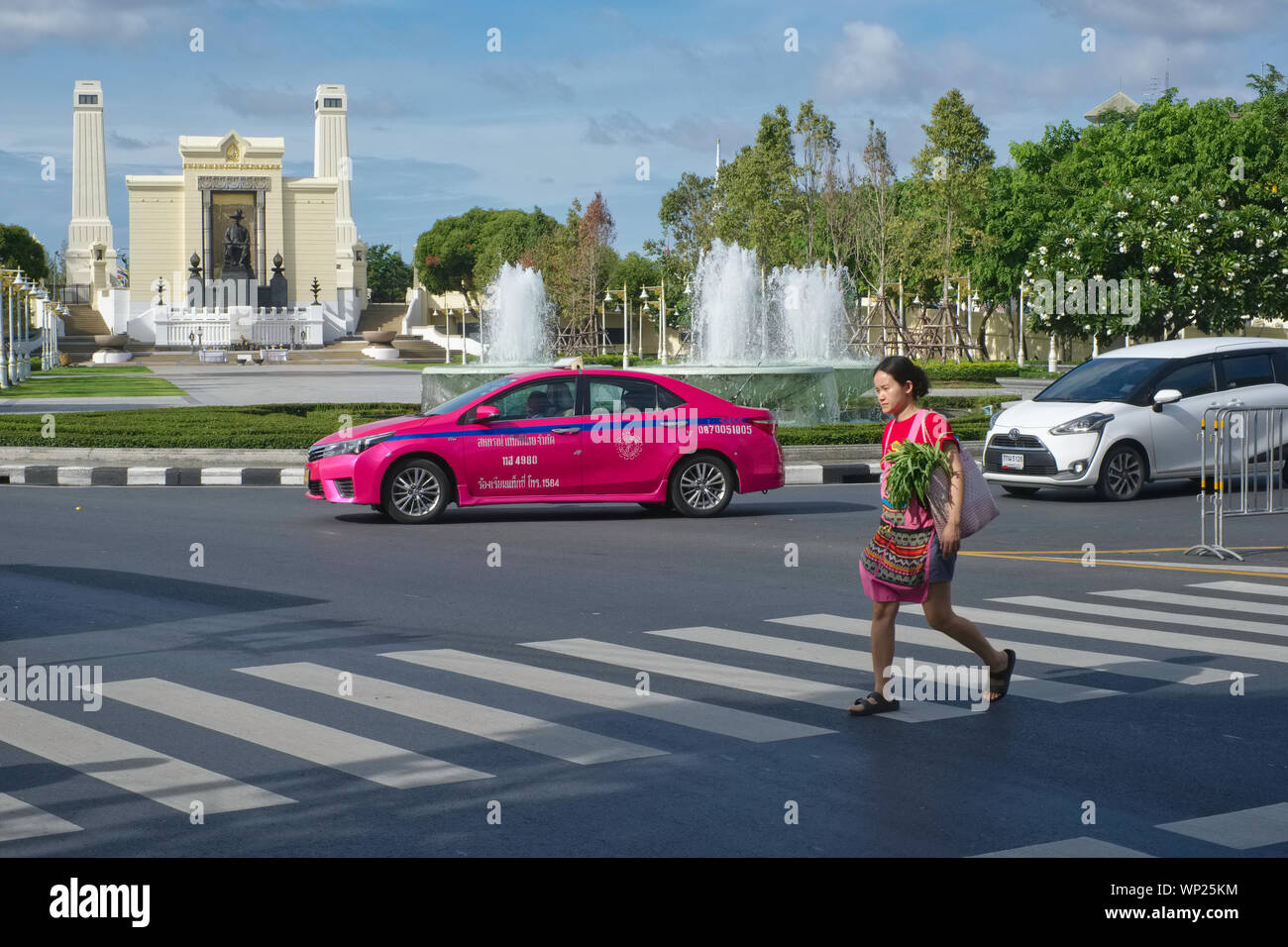 Une femme sur un passage clouté à Bangkok, Thaïlande, le Roi Rama I. Monument à b/g ; zebra frontaliers dans e sont largement ignorés par les automobilistes et dangereux Banque D'Images