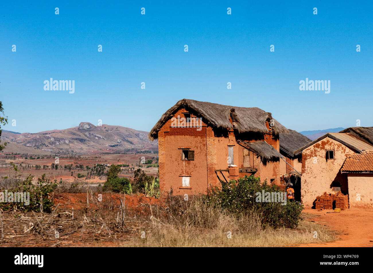 Typique de brique de boue traditionnelle en adobe construite de maisons de deux étages dans un petit village dans les hauts plateaux du centre de Madagascar. Briques orange foncé Banque D'Images