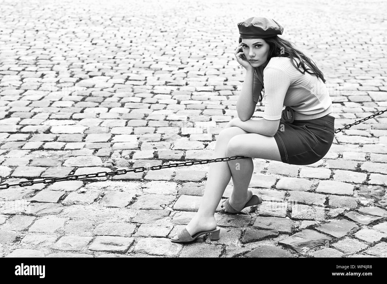 Jeune belle brunette girl émotionnel habillé en retro vintage style dans l'ancienne ville se trouve d'une chaîne Banque D'Images