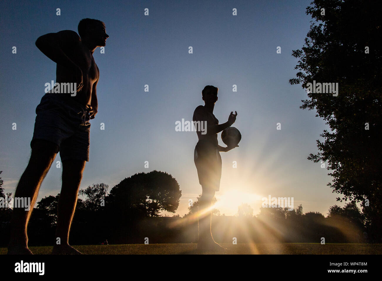 Deux garçons prendre et transmettre un ballon de rugby sur une journée d'été dans un parc, de formation pour la nouvelle saison Banque D'Images