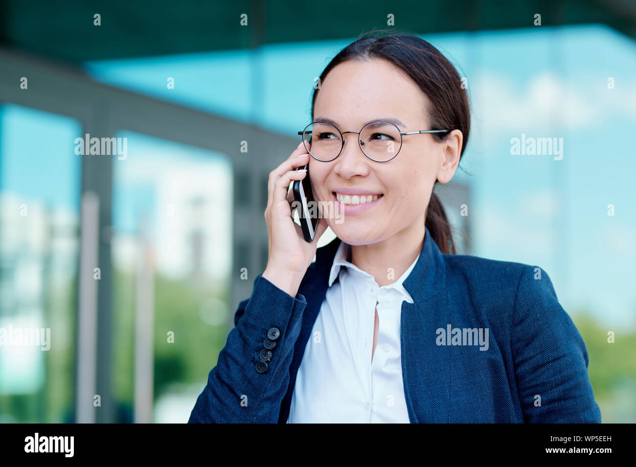 Jeune brunette smiling businesswoman discussion moments de travail sur smartphone Banque D'Images