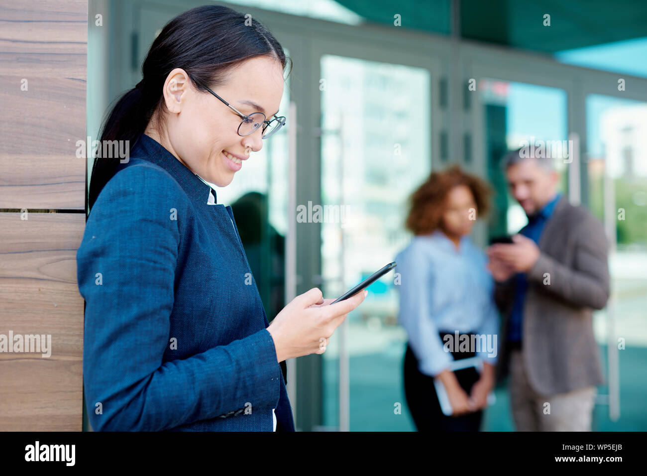 Happy young brunette femme défilant ou la lecture de message dans smartphone outdoors Banque D'Images