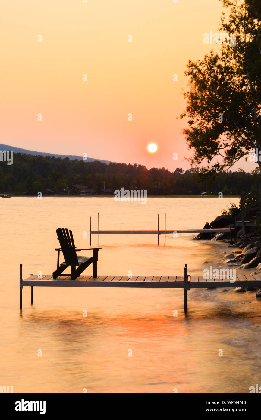 Chaise Adirondack sur le bout d'un quai au coucher du soleil sur le lac Willoughby, New York, USA Banque D'Images