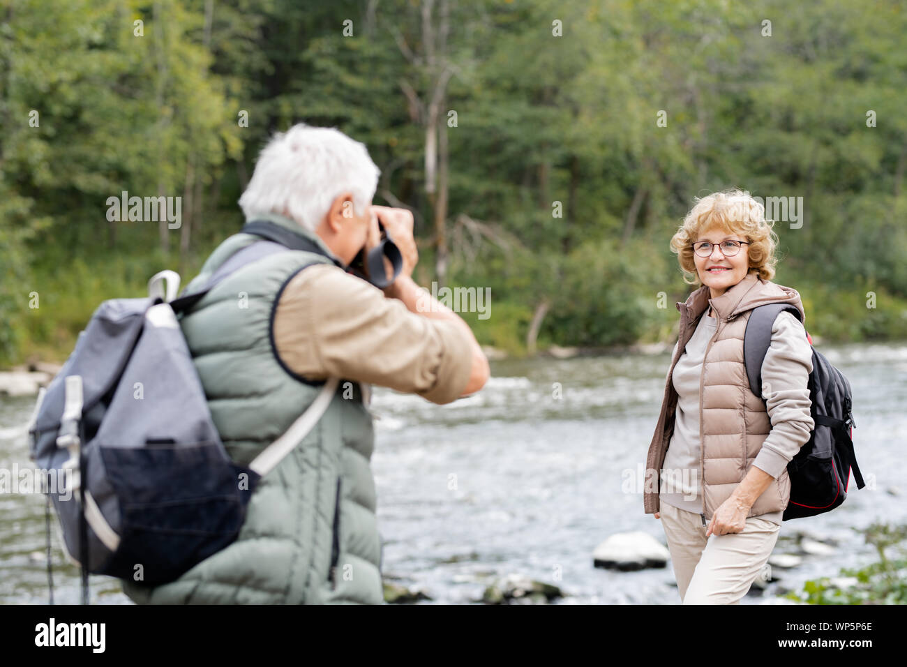 Actif mature backpacker photographier sa femme heureuse sur les bords de la rivière Banque D'Images