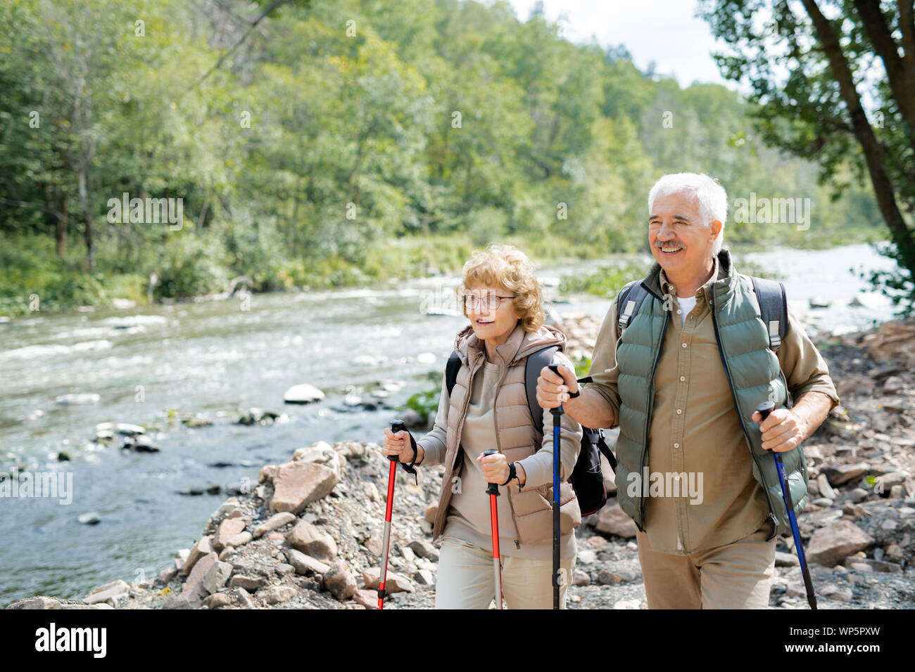 Mature les randonneurs avec sacs à dos et bâtons de trekking randonnée pédestre le long de riverside Banque D'Images