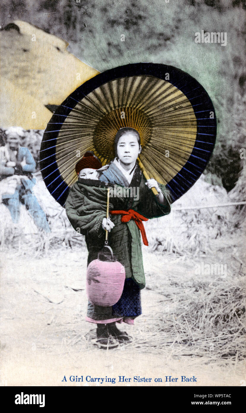 [ 1900 - Japon ] Nursemaid Enfant Japonais - une jeune fille tenant un parasol en papier et un chochin (lanterne) porte un bébé sur son dos. Bien que la légende membres elles sont sœurs, la fille plus âgée pourrait aussi être un komori. Komori étaient de jeunes filles de familles pauvres qui ont été engagés par l'année d'aider les mères de classe moyenne et supérieure dans le soin de leur enfant. En plus d'effectuer le bébé autour, la komori pourrait aussi aider un peu avec les travaux ménagers. Komori a reçu de la nourriture, le logement, les vêtements, et parfois un peu d'argent. 20e siècle vintage carte postale. Banque D'Images