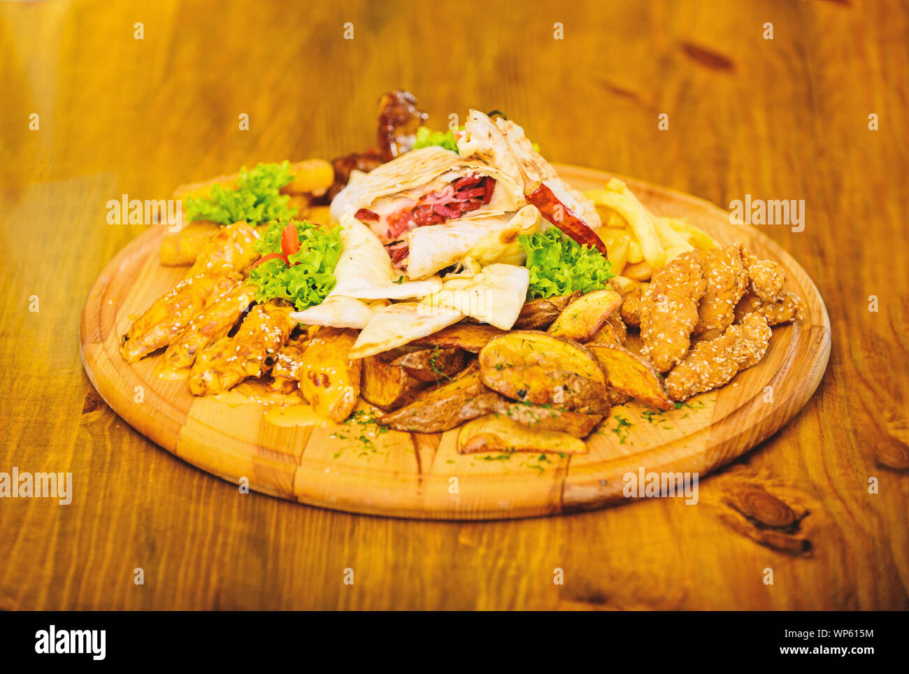 De délicieux en-cas savoureux. Les repas au restaurant. Snack pour la bière. Planche de bois avec beaucoup de frites et bâtonnets de poisson viande burrito steak servi avec une salade. Menu snack-bar. Calories élevé pour le groupe d'amis. Banque D'Images