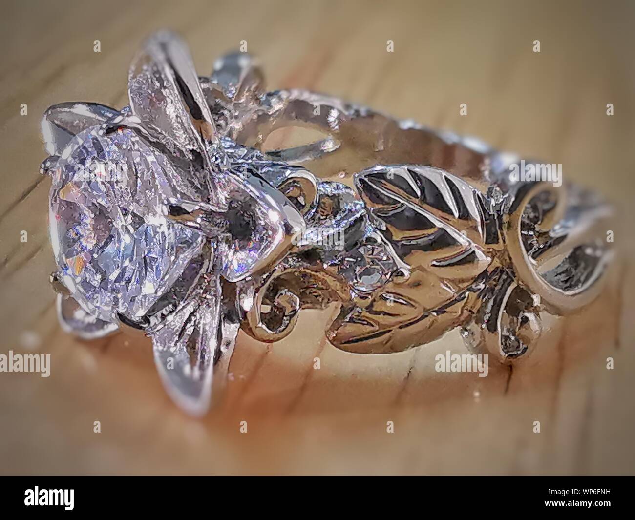 Blanc DIAMANT BAGUE ARGENT ALUMINIUM ACIER CORPS LIBRE AVEC DESIGN FLEUR ET FEUILLE MACRO IMAGE CRYSTAL SHINE SUR UNE TABLE Banque D'Images