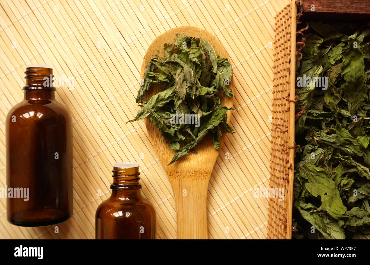 Feuilles de menthe poivrée biologique dans la cuillère en bambou et dans la boîte. Herbe séchée préparée pour faire du thé ou de l'extrait pour les besoins médicaux ou cosmétiques Banque D'Images