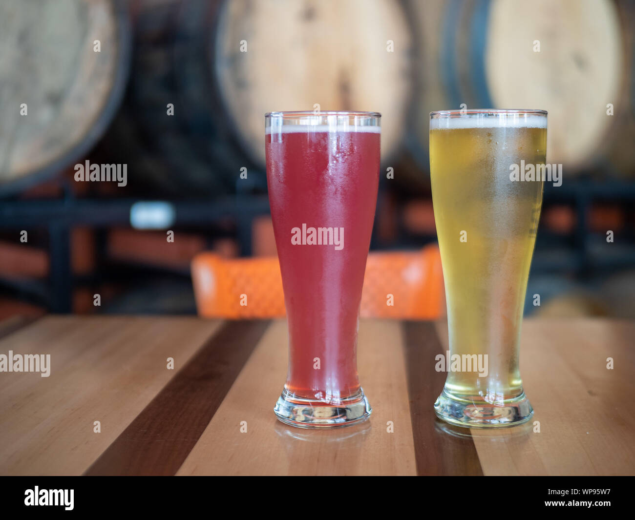 Blonde et Rose froid grands verres de bière sur la table en face de barils en brasserie Banque D'Images